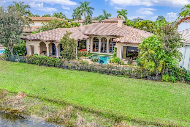 rear view of house with a fenced in pool, a yard, and a patio area