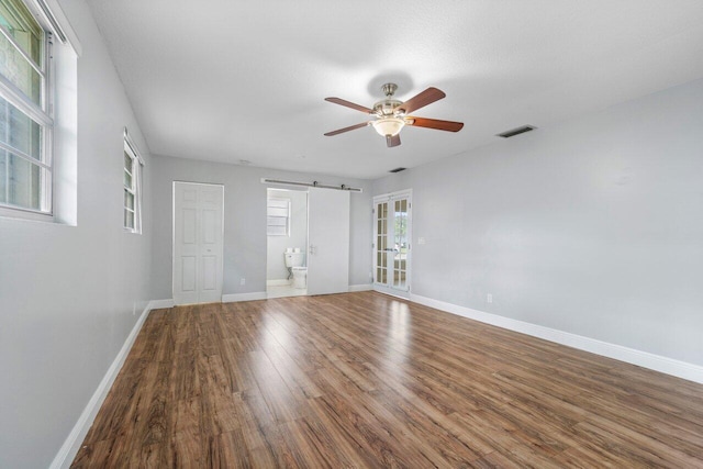 empty room featuring hardwood / wood-style floors, a barn door, and ceiling fan