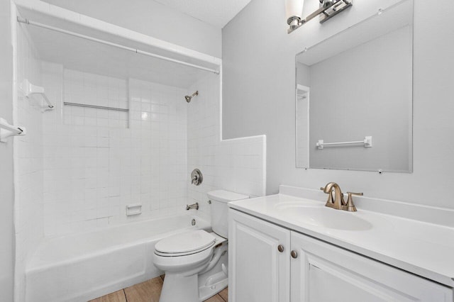 full bathroom with tiled shower / bath combo, vanity, hardwood / wood-style flooring, toilet, and a textured ceiling