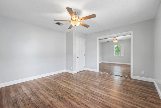 unfurnished bedroom featuring dark hardwood / wood-style floors, a textured ceiling, a closet, and ceiling fan