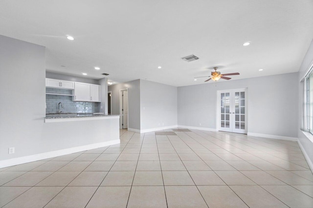 unfurnished living room with sink, light tile patterned floors, french doors, and ceiling fan