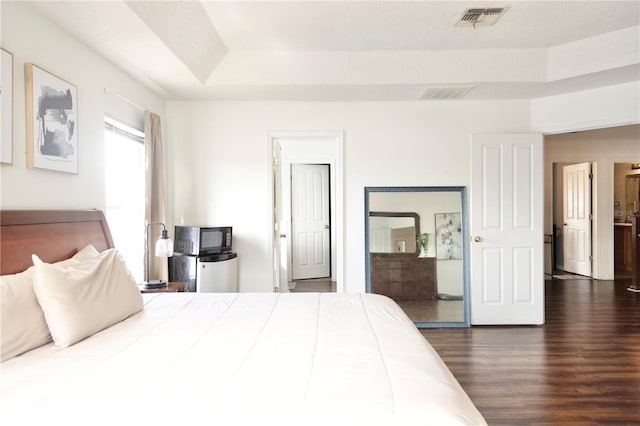 bedroom featuring a raised ceiling and dark hardwood / wood-style flooring