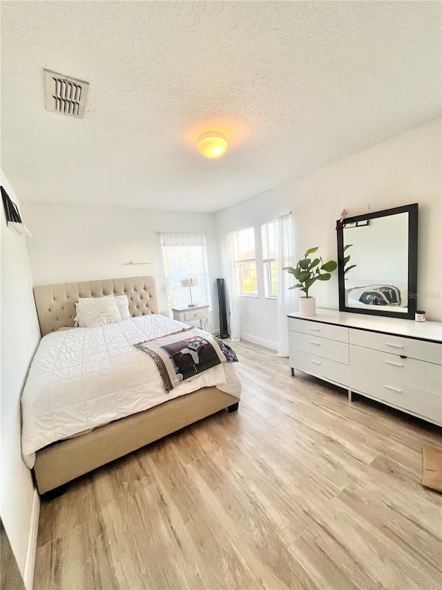 bedroom with a textured ceiling and light wood-type flooring