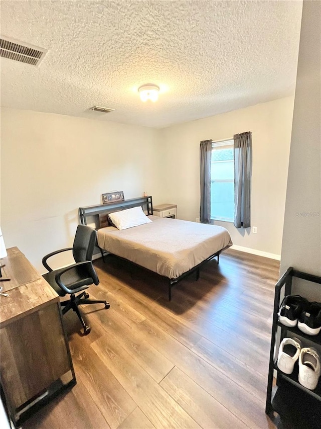 bedroom featuring light wood-type flooring and a textured ceiling