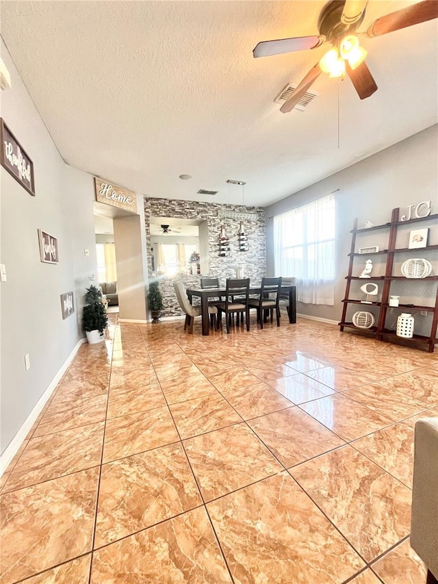 unfurnished dining area with ceiling fan and a textured ceiling