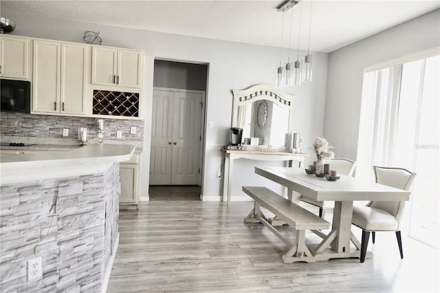 dining area with light hardwood / wood-style floors, a textured ceiling, and bar area