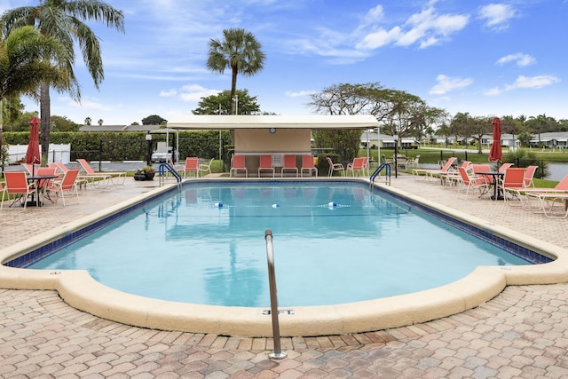 view of swimming pool featuring a patio and an outdoor bar