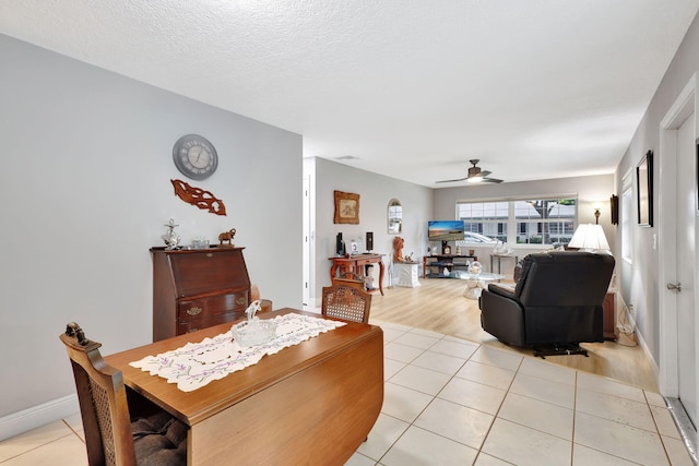 living room with ceiling fan, light tile patterned floors, and a textured ceiling