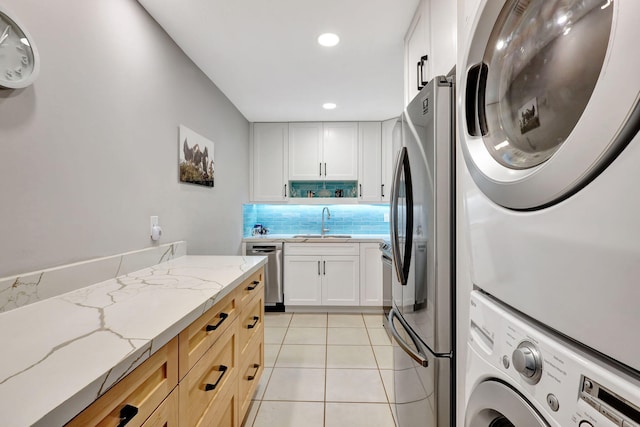 washroom featuring stacked washer and dryer, light tile patterned floors, and sink