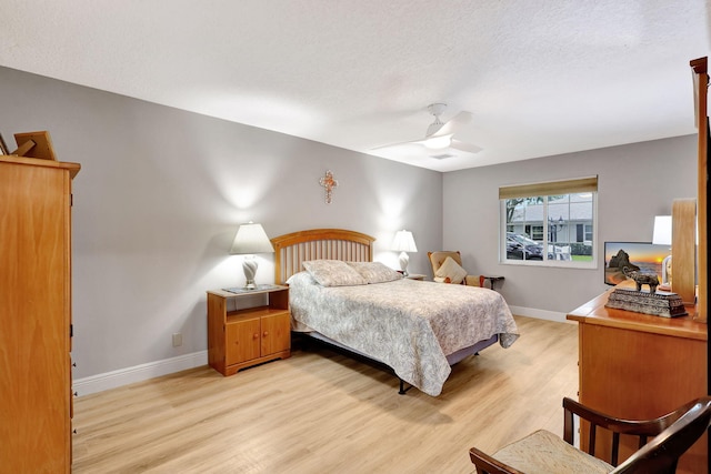 bedroom with ceiling fan, a textured ceiling, and light hardwood / wood-style flooring