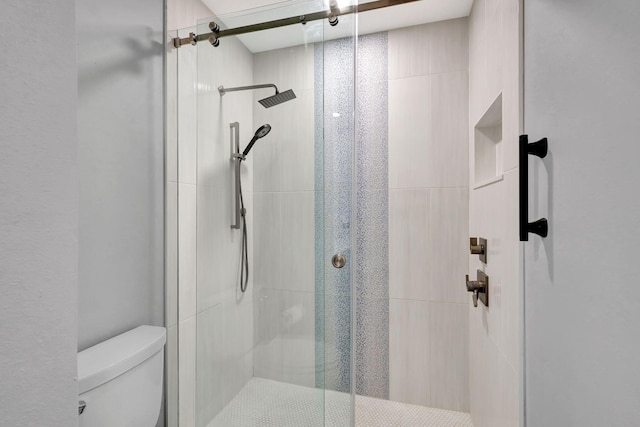 bathroom with toilet and a shower with shower door