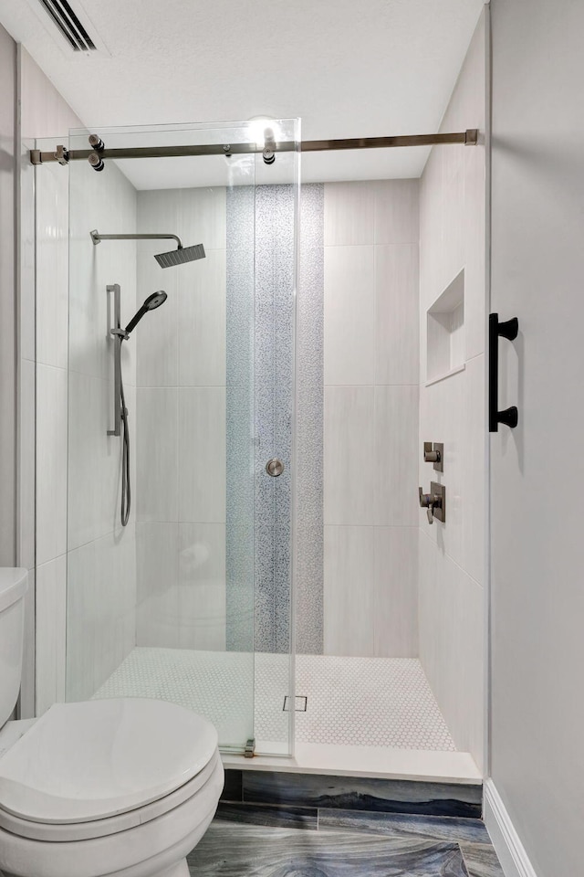 bathroom featuring toilet, a shower with door, and hardwood / wood-style floors