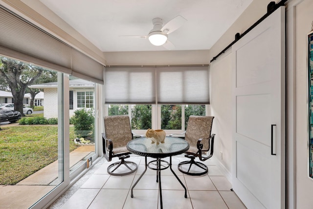 sunroom featuring ceiling fan, a barn door, and plenty of natural light