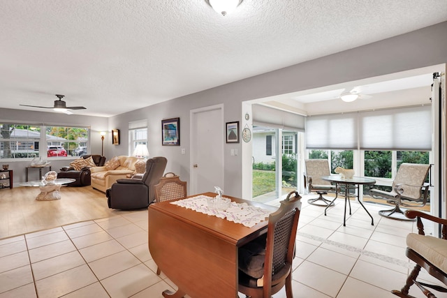 tiled dining room with a textured ceiling, ceiling fan, and a healthy amount of sunlight