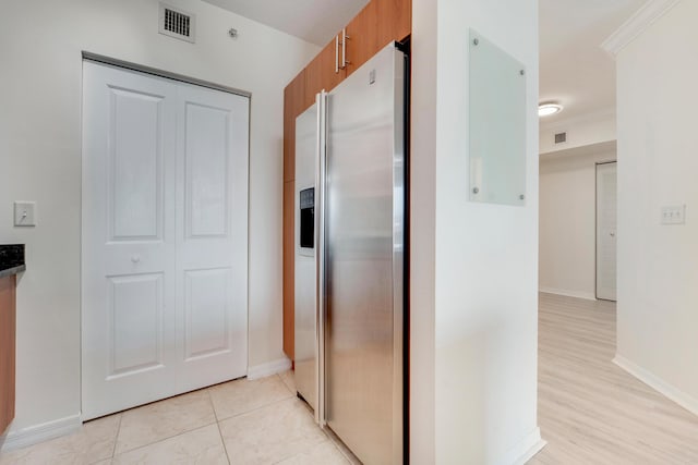 kitchen featuring light tile patterned floors, stainless steel fridge with ice dispenser, and ornamental molding