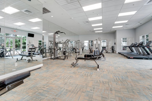 exercise room with a drop ceiling, carpet flooring, a high ceiling, and french doors