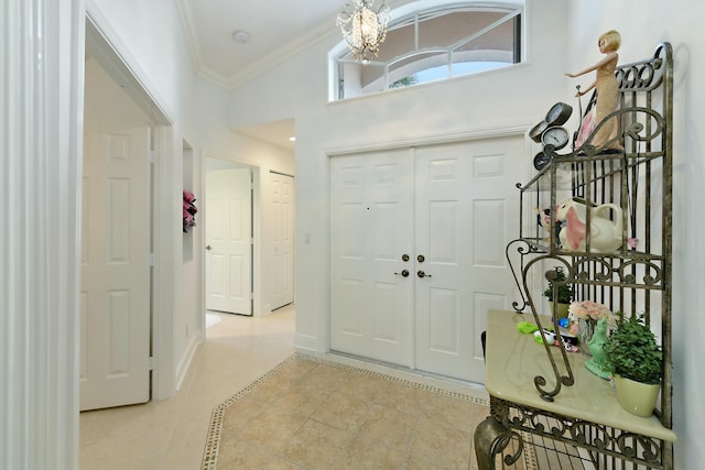 tiled entrance foyer featuring crown molding, an inviting chandelier, and high vaulted ceiling