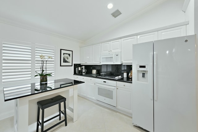 kitchen featuring lofted ceiling, backsplash, a kitchen breakfast bar, white cabinets, and white appliances