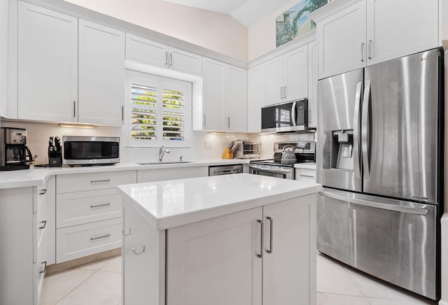 kitchen with white cabinets, appliances with stainless steel finishes, vaulted ceiling, sink, and light tile patterned flooring