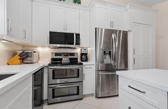 kitchen with light tile patterned floors, stainless steel appliances, and white cabinetry