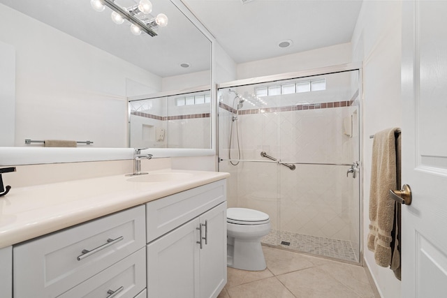 bathroom featuring toilet, vanity, tile patterned flooring, and a shower with door