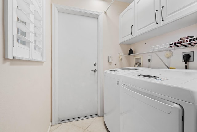 laundry room featuring light tile patterned flooring, washing machine and clothes dryer, and cabinets