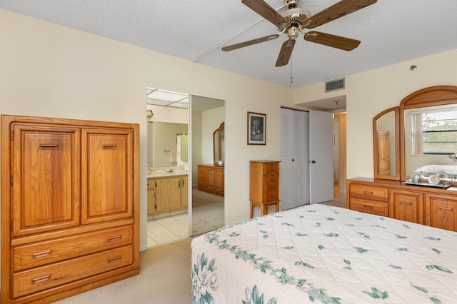 carpeted bedroom with a textured ceiling, ceiling fan, a closet, and connected bathroom