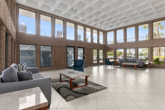 living room with coffered ceiling, light tile patterned floors, and a high ceiling