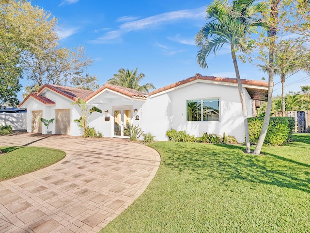 mediterranean / spanish-style house with a front lawn and french doors