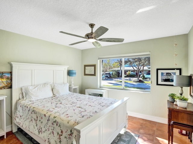 tiled bedroom with ceiling fan and a textured ceiling