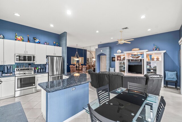 kitchen with ceiling fan, white cabinetry, dark stone counters, and light tile patterned floors