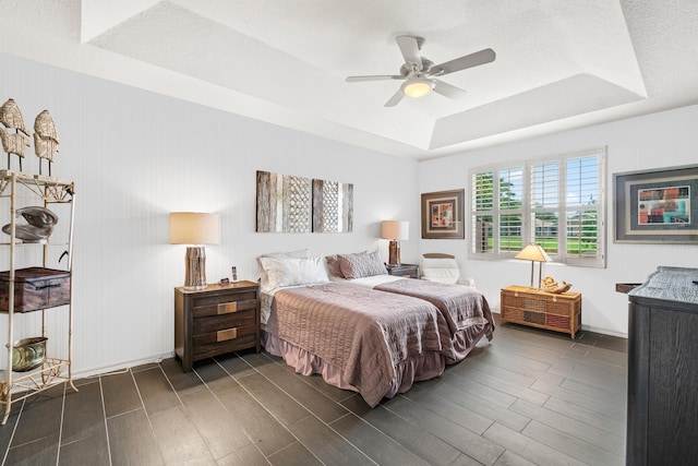 bedroom with a tray ceiling, ceiling fan, and dark hardwood / wood-style floors