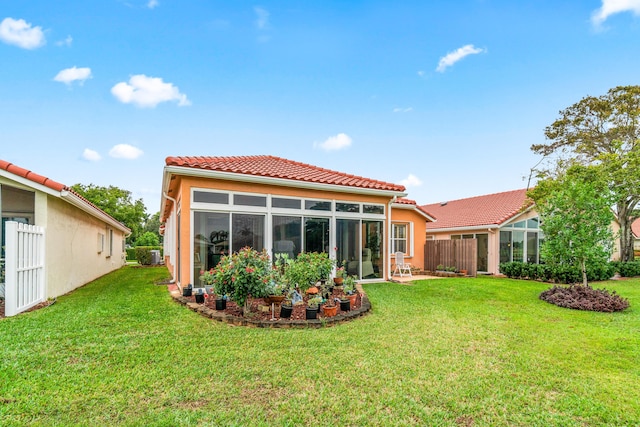 rear view of house with a yard and a sunroom