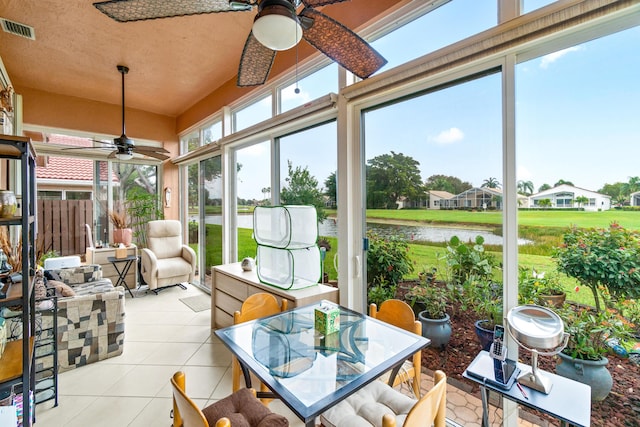 sunroom featuring ceiling fan and a water view