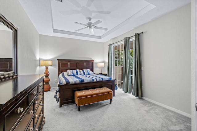 carpeted bedroom with a raised ceiling and ceiling fan