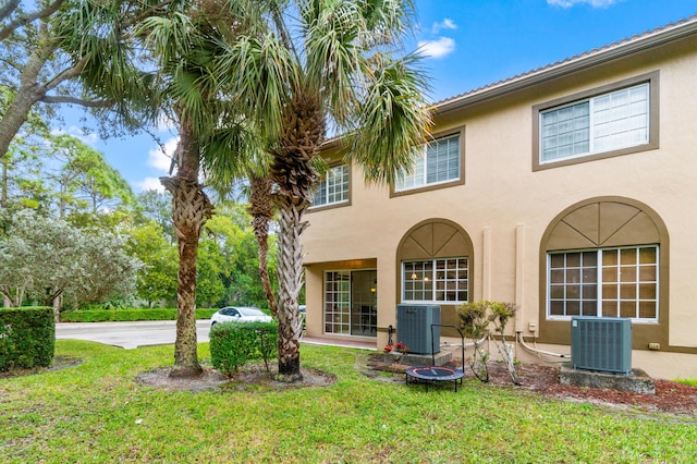 rear view of property with a lawn and central AC