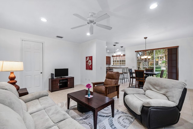 tiled living room featuring ceiling fan with notable chandelier