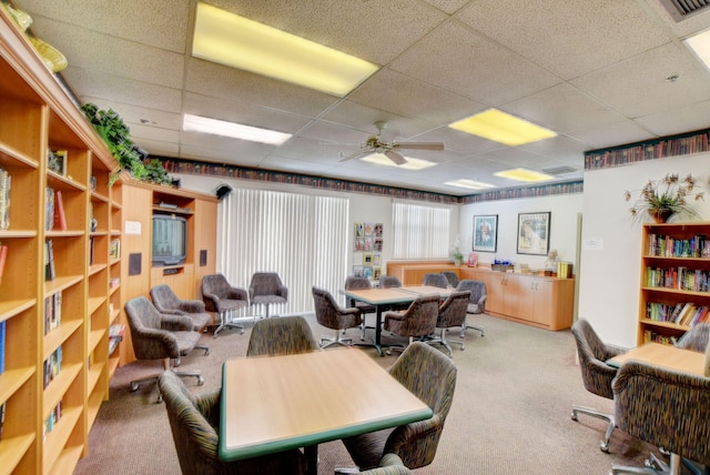 carpeted office space featuring ceiling fan and a drop ceiling