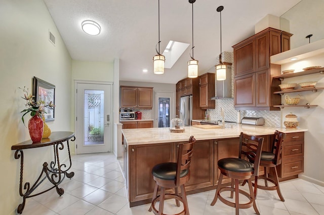 kitchen featuring a kitchen breakfast bar, pendant lighting, stainless steel fridge, backsplash, and lofted ceiling