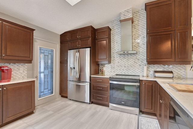 kitchen featuring light stone countertops, appliances with stainless steel finishes, wall chimney exhaust hood, decorative backsplash, and sink