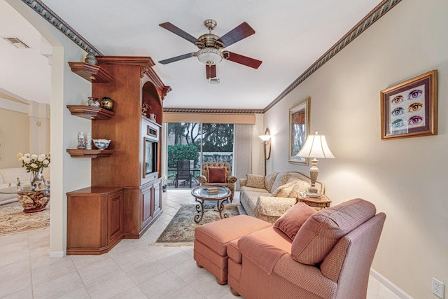 tiled living room with ceiling fan and crown molding