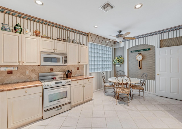 kitchen with appliances with stainless steel finishes, decorative backsplash, light tile patterned flooring, ceiling fan, and cream cabinetry