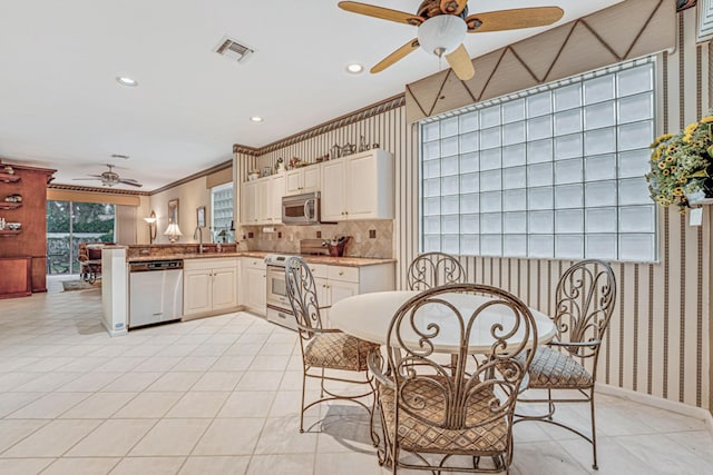 kitchen with kitchen peninsula, appliances with stainless steel finishes, decorative backsplash, crown molding, and sink