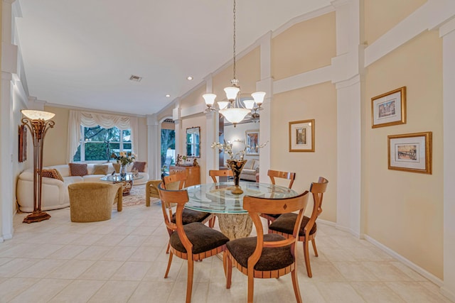 tiled dining space with lofted ceiling, ornamental molding, a chandelier, and ornate columns