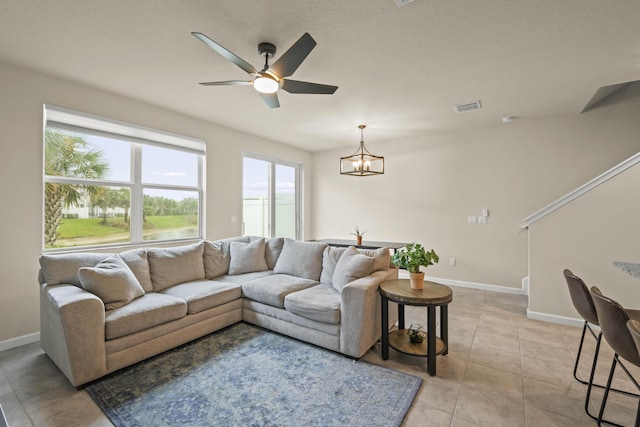 tiled living room featuring ceiling fan with notable chandelier