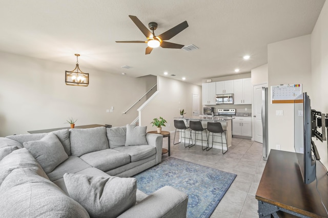 living room featuring ceiling fan with notable chandelier and light tile patterned floors