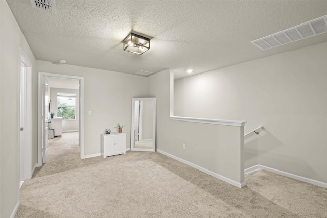 carpeted empty room with a textured ceiling