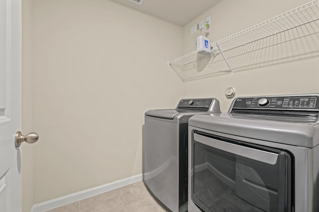 clothes washing area featuring light tile patterned flooring and washing machine and clothes dryer