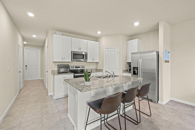 kitchen with sink, white cabinets, appliances with stainless steel finishes, and a kitchen island with sink