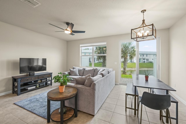 tiled living room featuring ceiling fan with notable chandelier